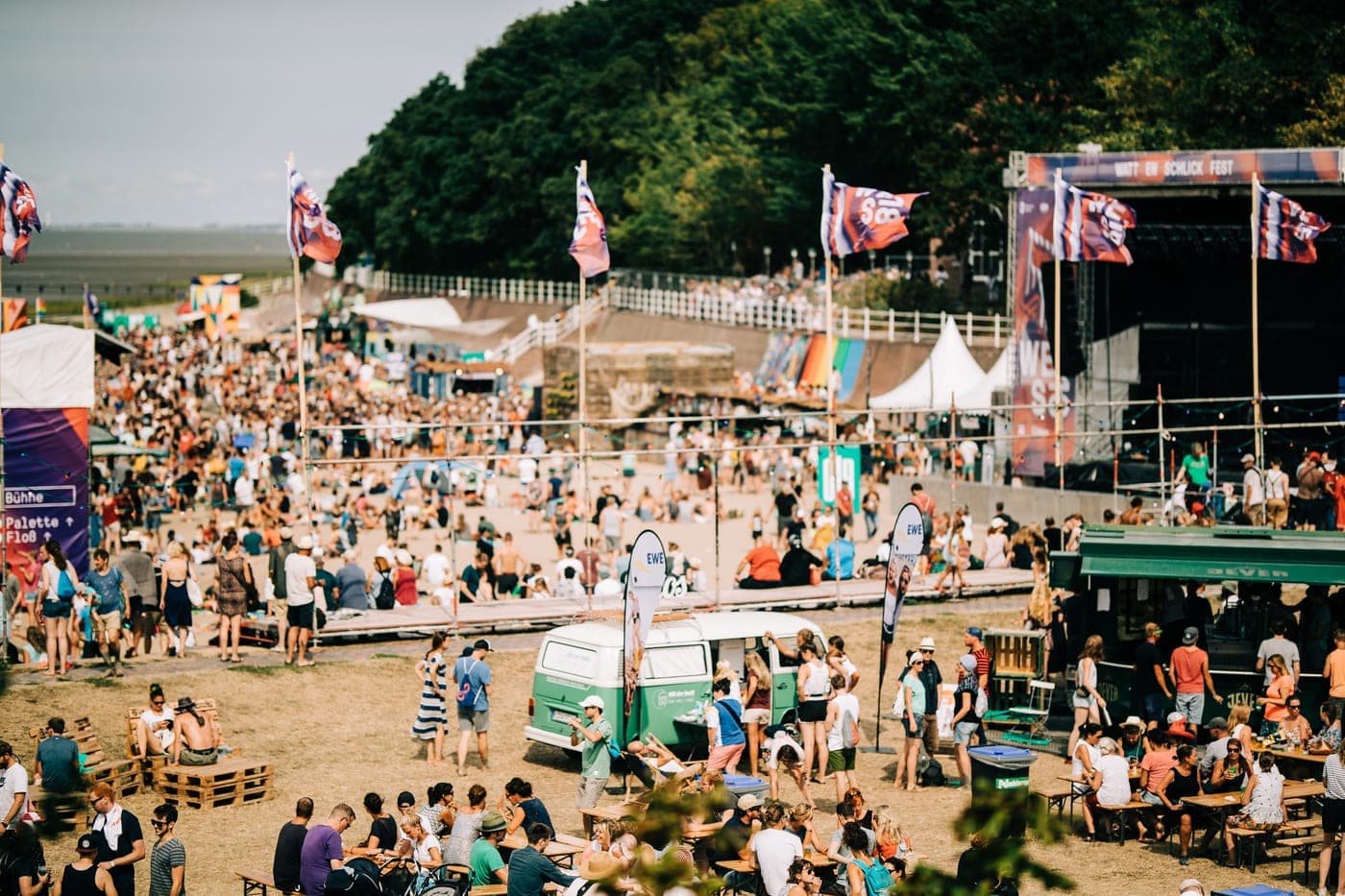 Der Fotobulli mitten im Festivaltrubel, umringt von Besuchern zwischen Bierbänken und Bühne